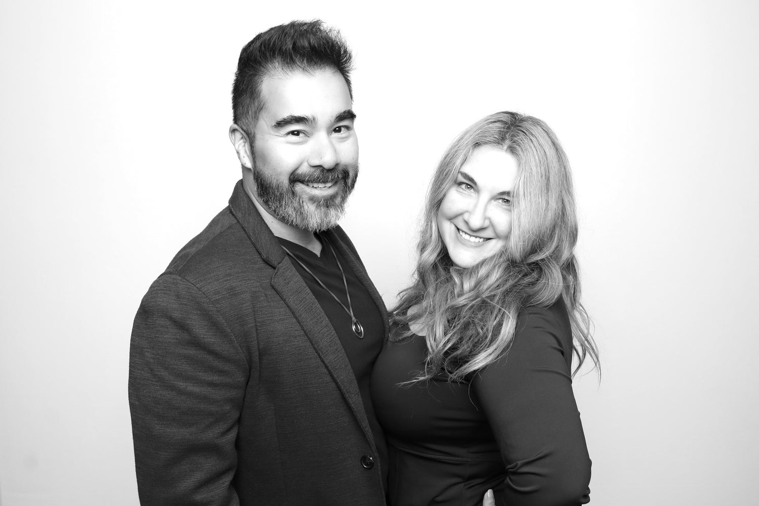 Black and white photo of a man and woman posing together against a plain background