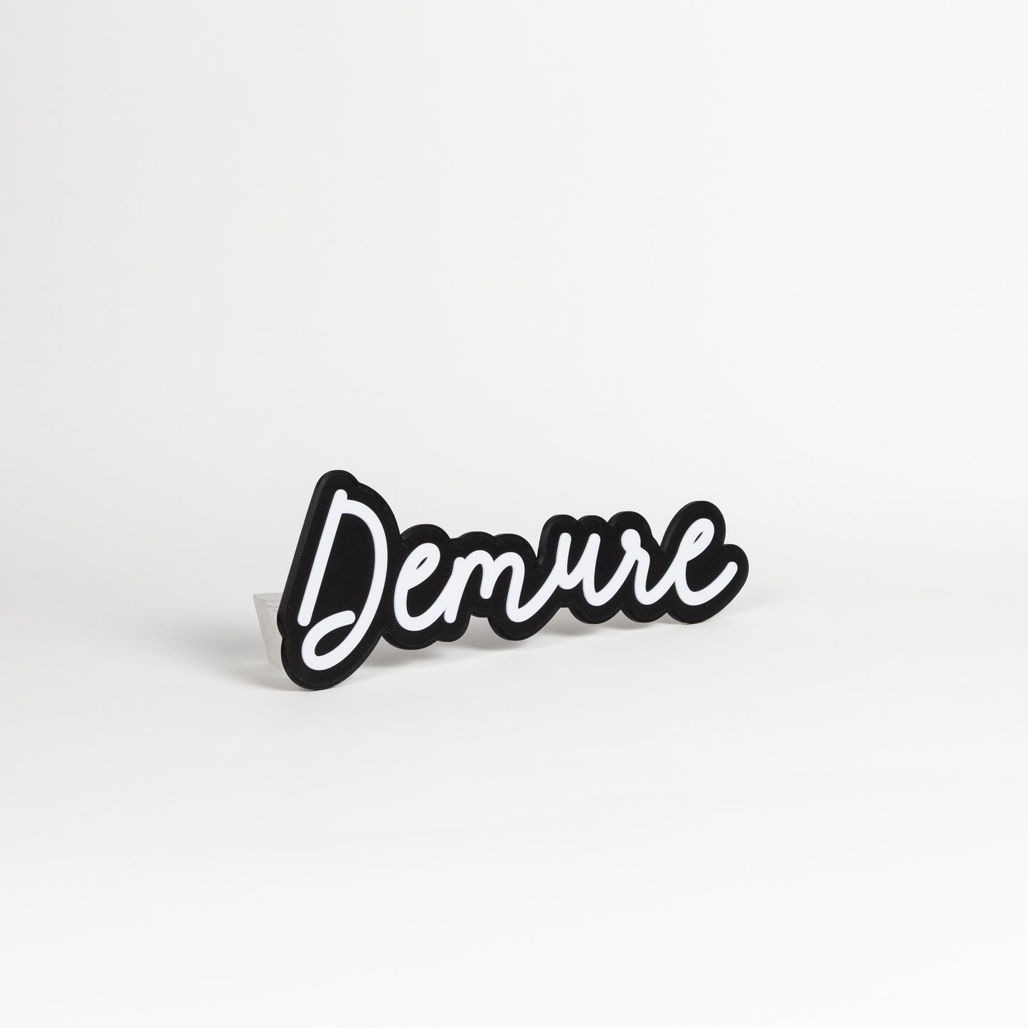 Black and white 'Demure' photo booth sign on white background.