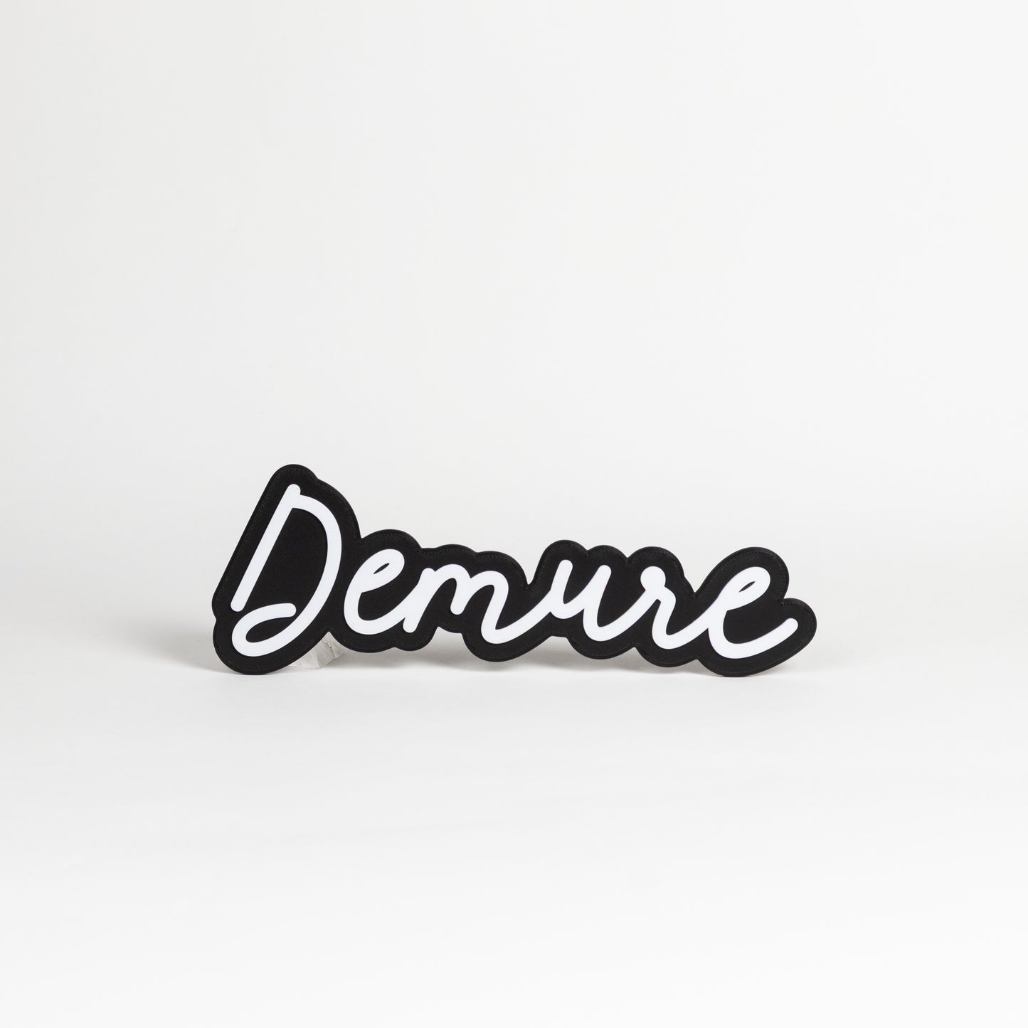 Black and white 'Demure' sign on a white background.