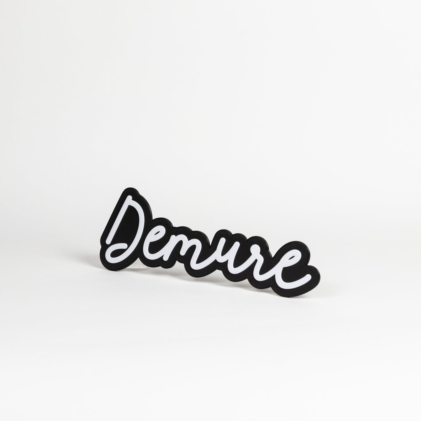 Ortho view of Black and white 'Demure' photo prop sign on a white background
