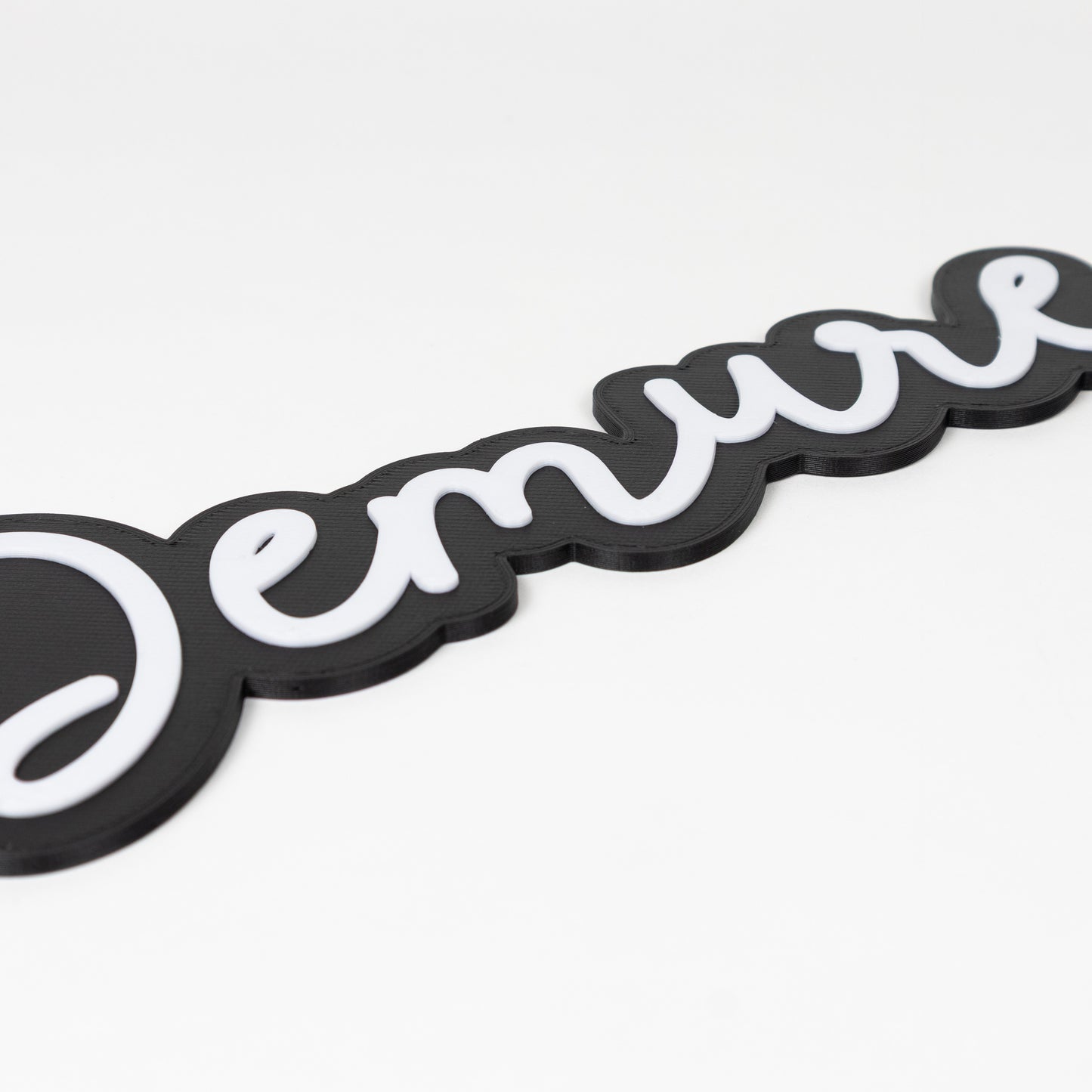 Black and white 'Demure' photo booth prop sign on a white background. Close up on raised white lettering.