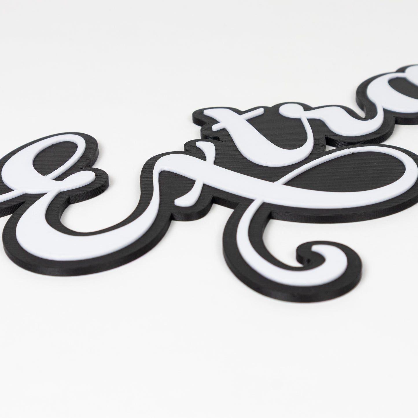 Close up shot of photo booth prop sign "Extra". Features raised white letters on a matte black base. Shot on a white background.