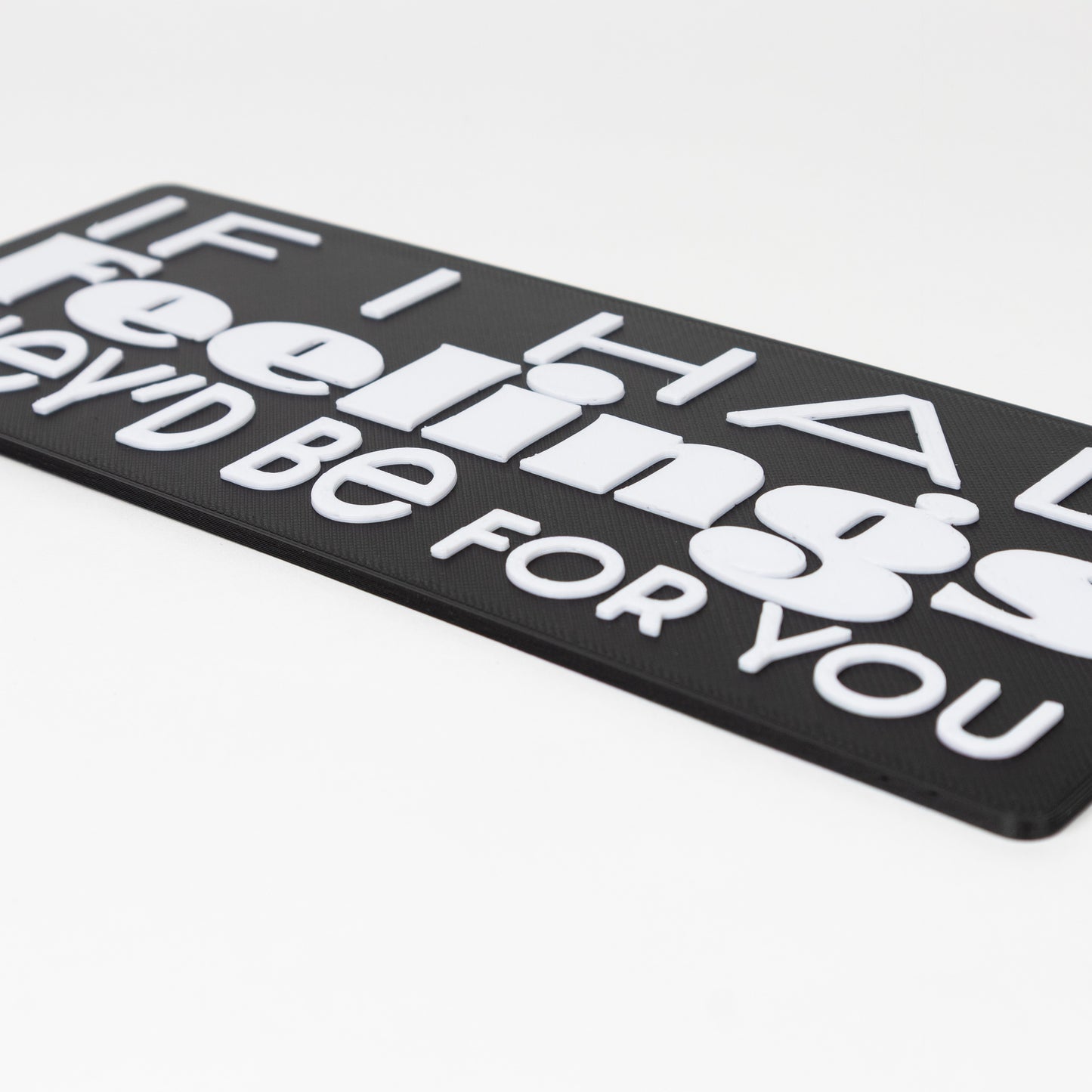 Close up shot of black sign with white raised text on a white background that says, "If I had feelings, they'd be for you"