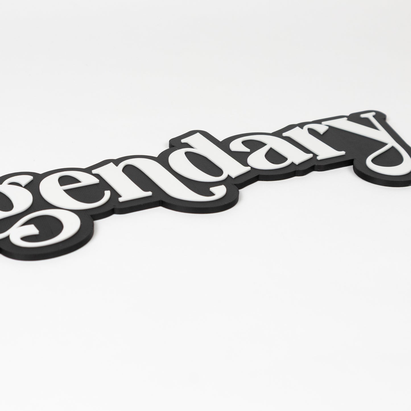 Close up shot of a photo booth prop sign. Black base with raised white 'legendary' text on a white background