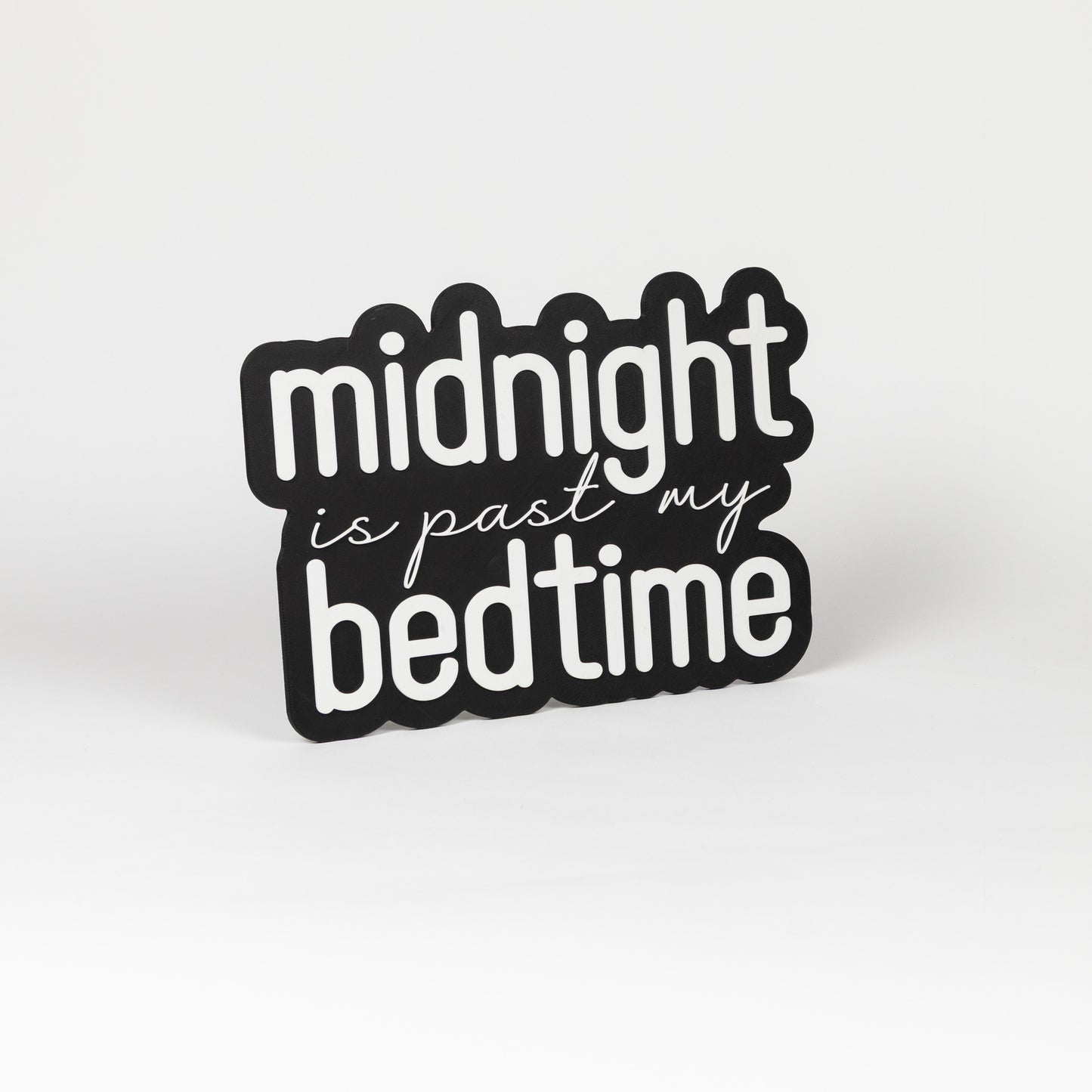 Photo booth prop sign. Black base with 'midnight is past my bedtime' white text on a white background