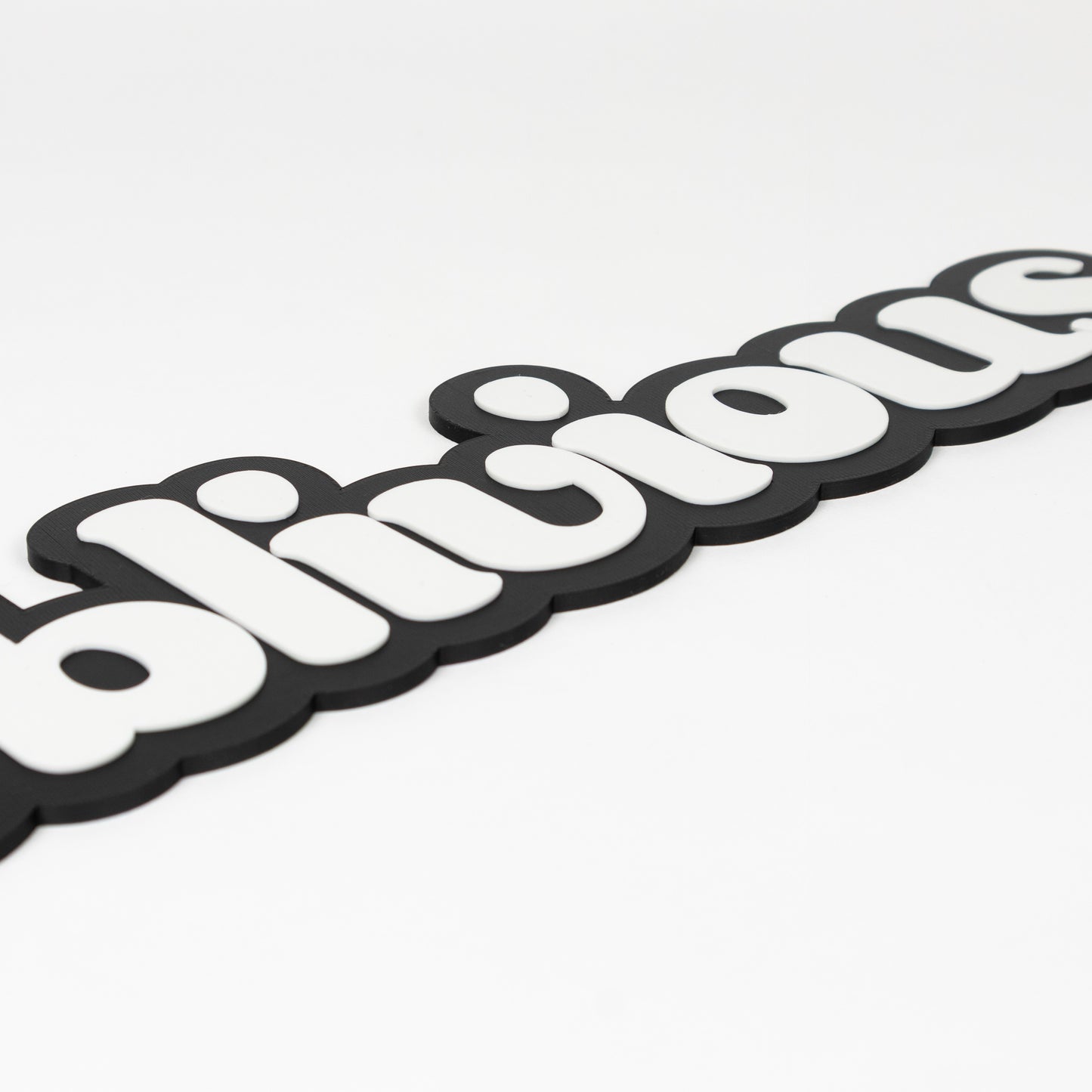 Close up of a photo booth prop that says, "oblivious". Show raised white text on a black base.