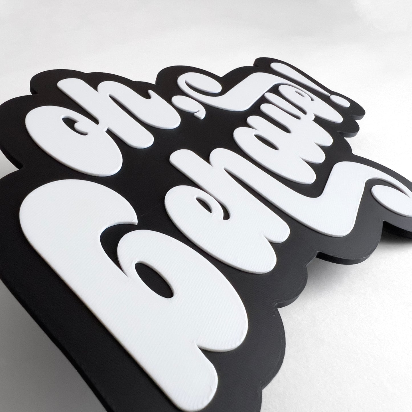 Close up of a black and white photo booth prop sign that says "oh, behave!". Shows raised lettering.