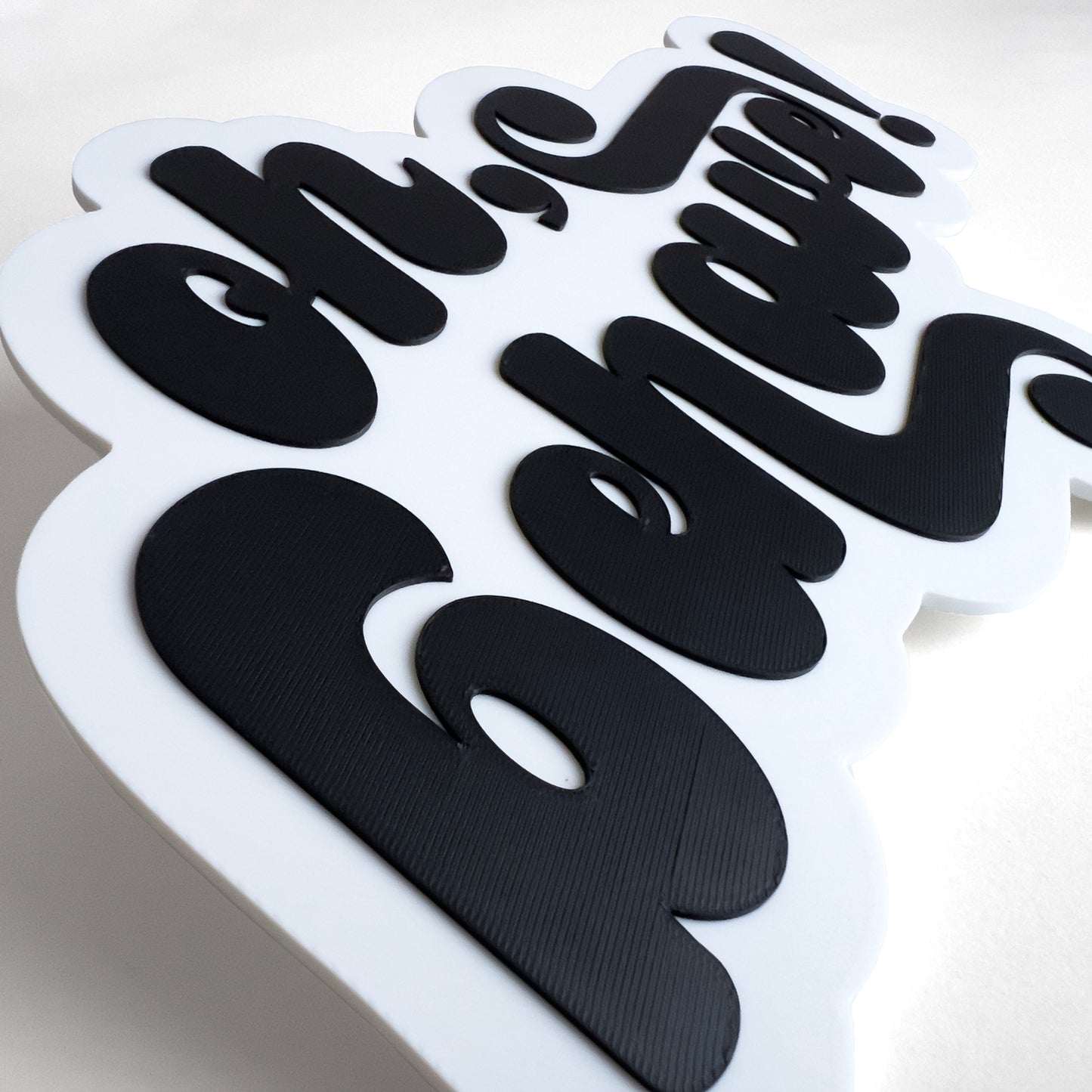 Close up of a white and black photo booth prop sign that says "oh, behave!". Shows raised lettering.