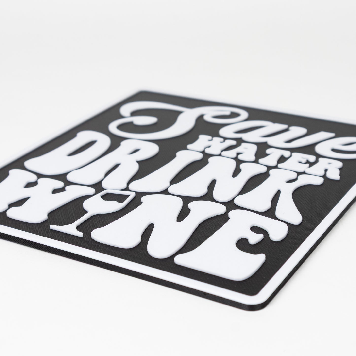 Close up of black and white sign that says, "Save Water, Drink Wine". Shows raised white text on a black silhouette base. Photo booth prop.