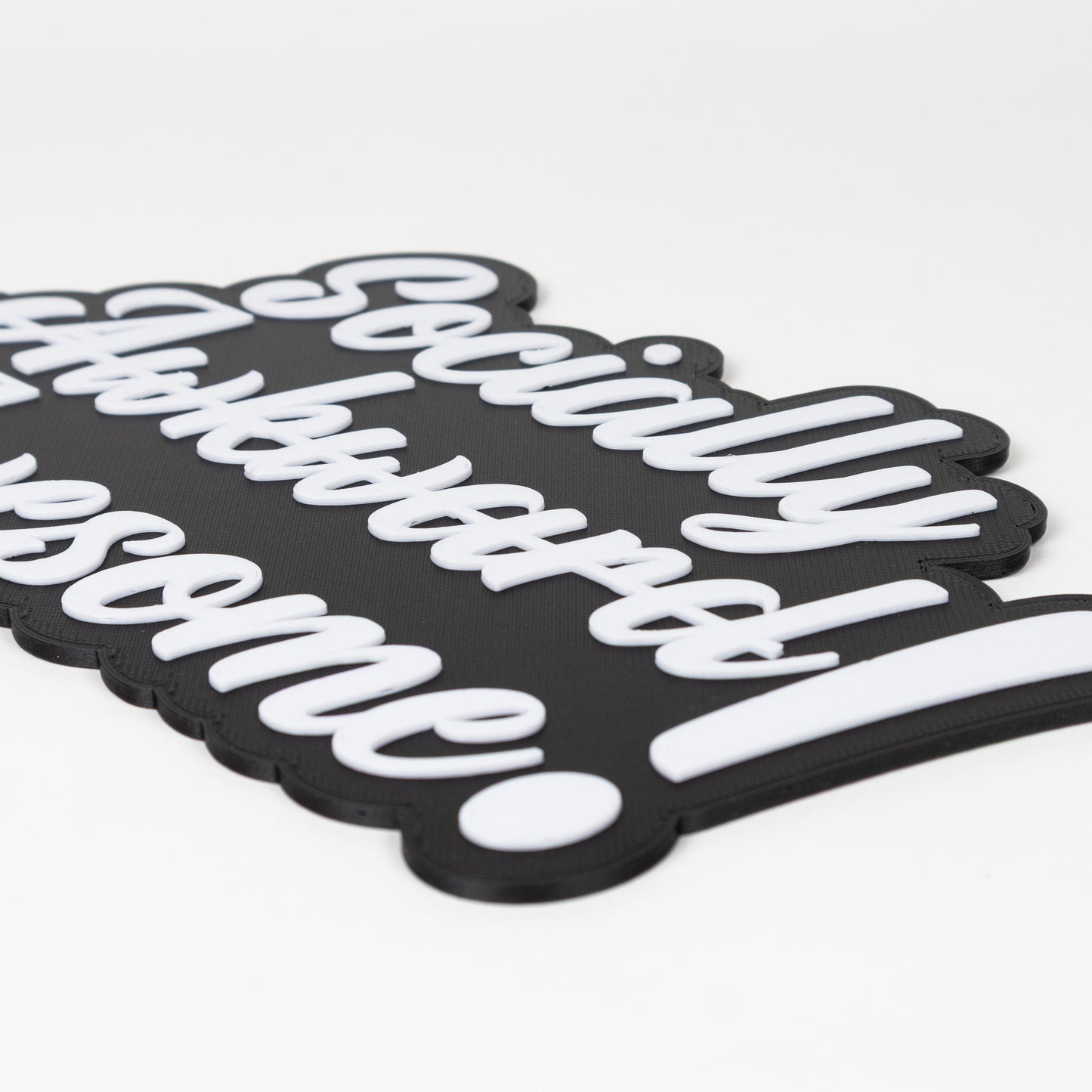 Close up of black and white sign that says, "Socially Awkward Awesome!". Shows raised white text on a black base. Photo booth prop.