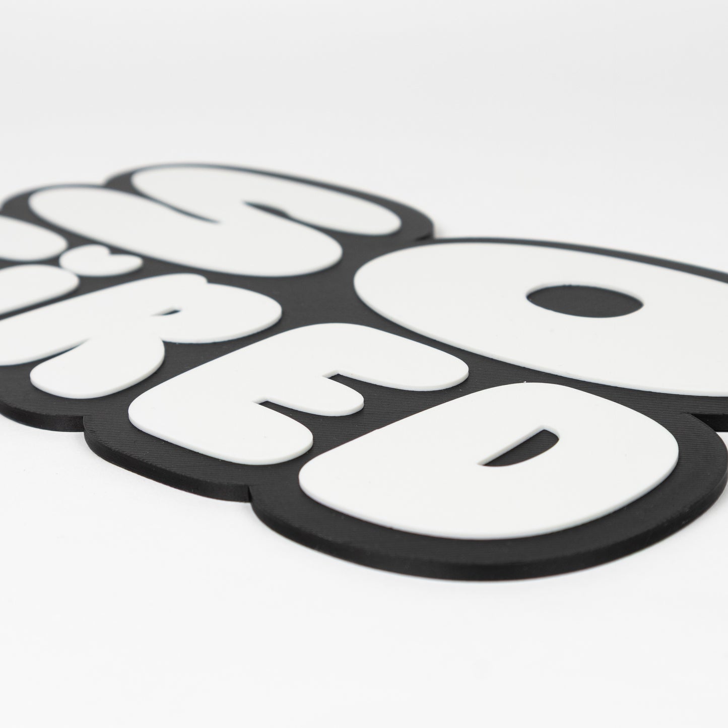 Close up of black and white "So Tired" sign that shows raised white text on black silhouette base. Photo booth prop.