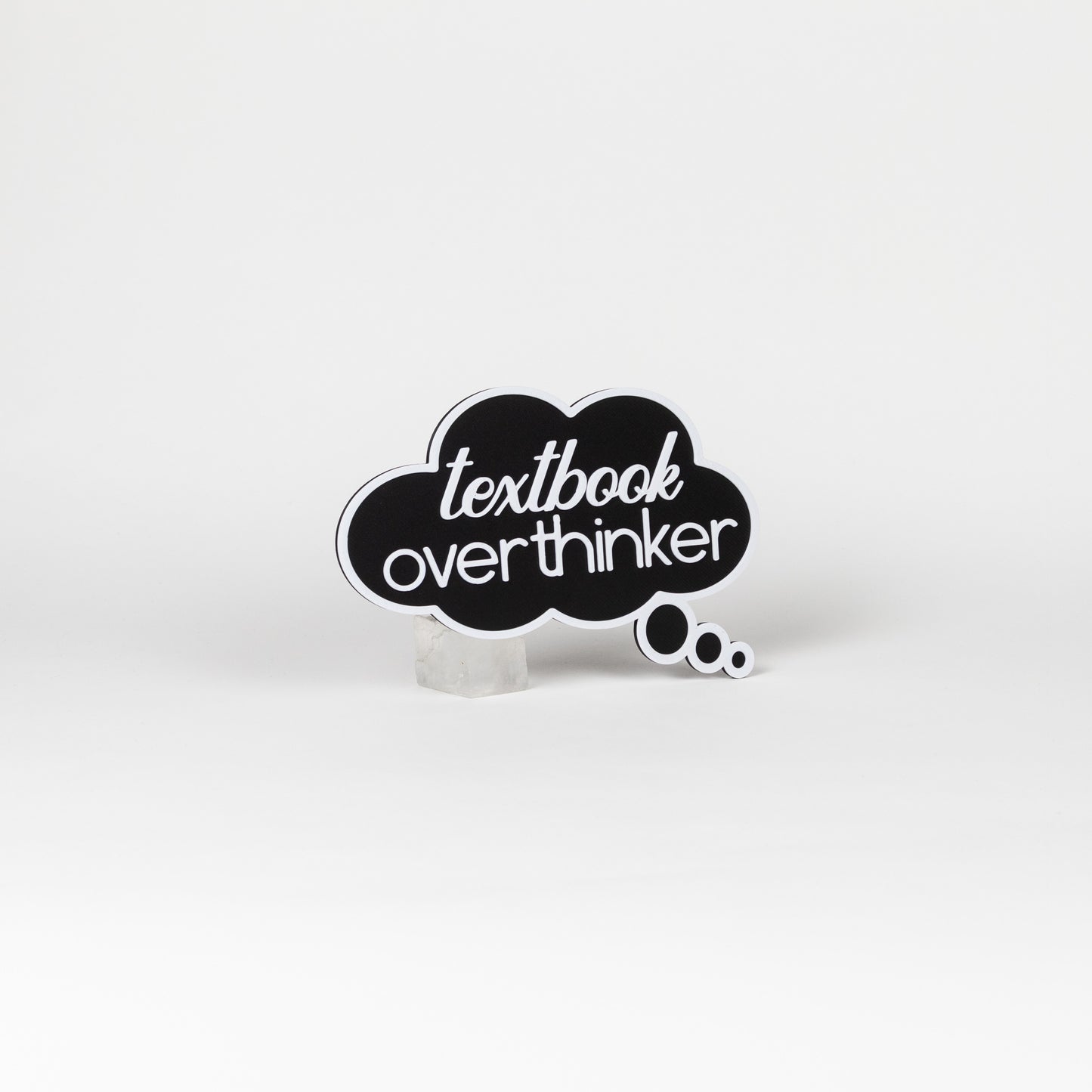 Black cloud-shaped sign with 'textbook overthinker' text in white. Photo booth prop shot on a white background.