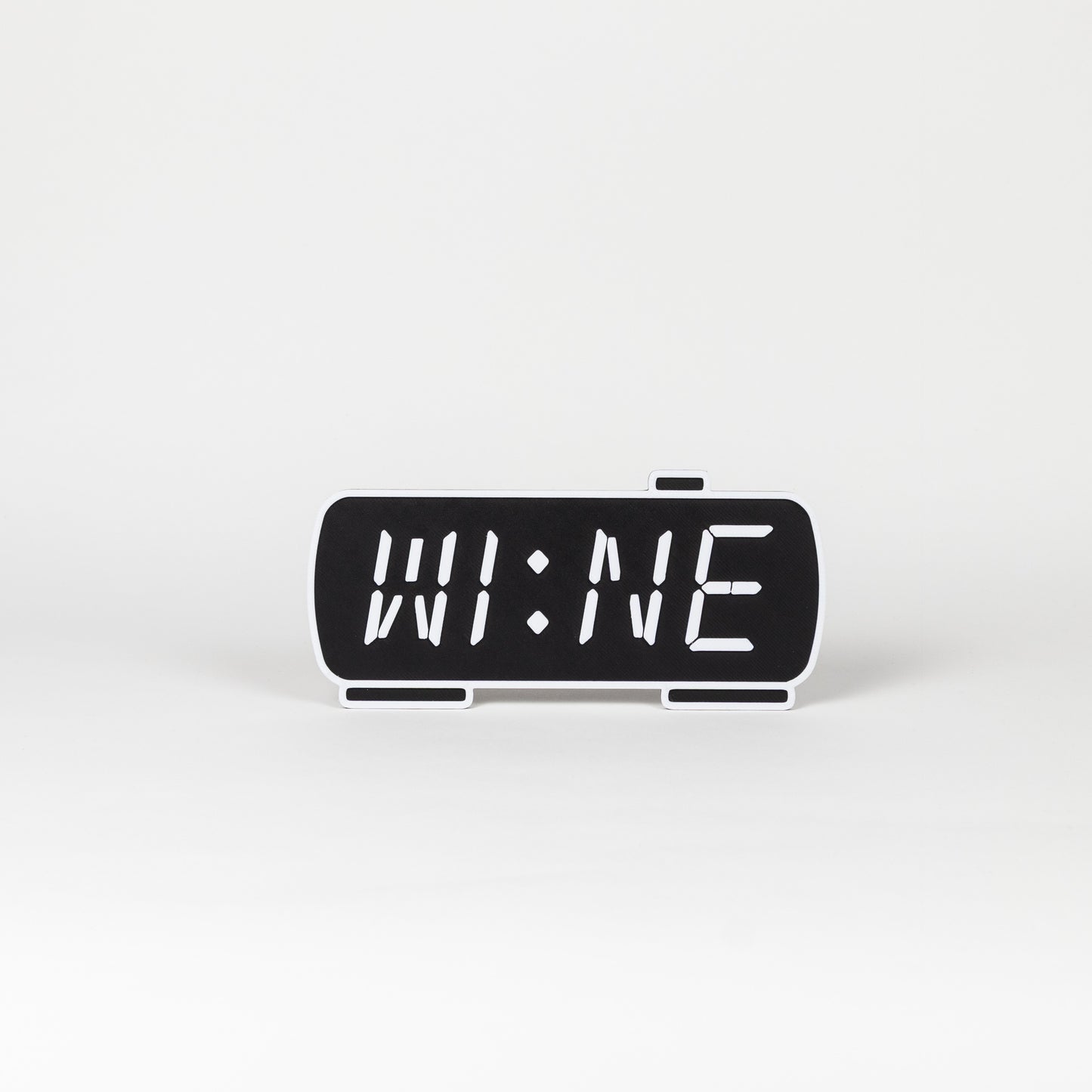 Black and white photo prop of a digital clock displaying 'WINE'.
