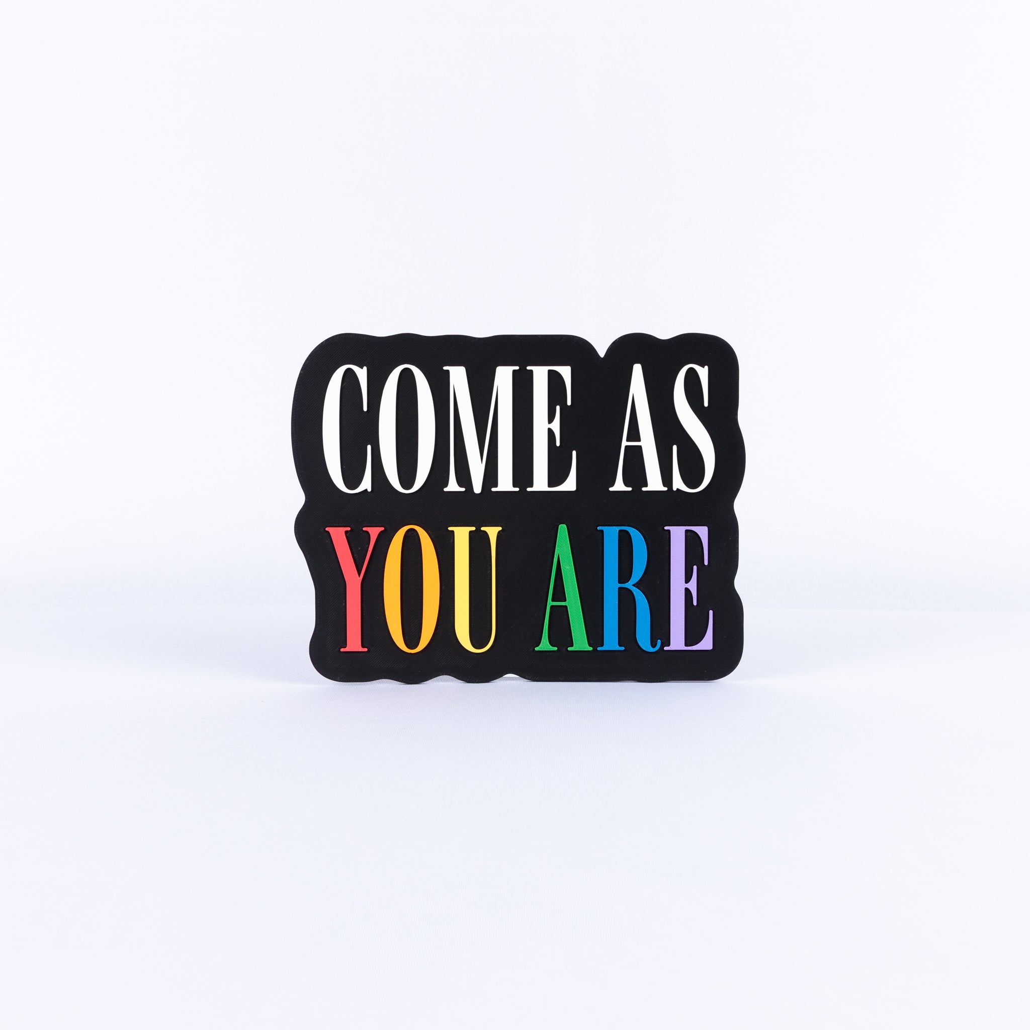 'COME AS YOU ARE' sign with 'YOU ARE' in colorful letters on a white background