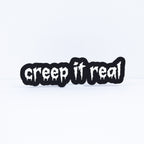 3D printed black sign with white stylized text that says, "creep it real". Shot on a white background.