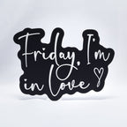 A 3D printed sign with white text on a black base that says, "Friday, I'm In Love" with a heart at the end. Inspired by The Cure song, Friday I'm In Love.