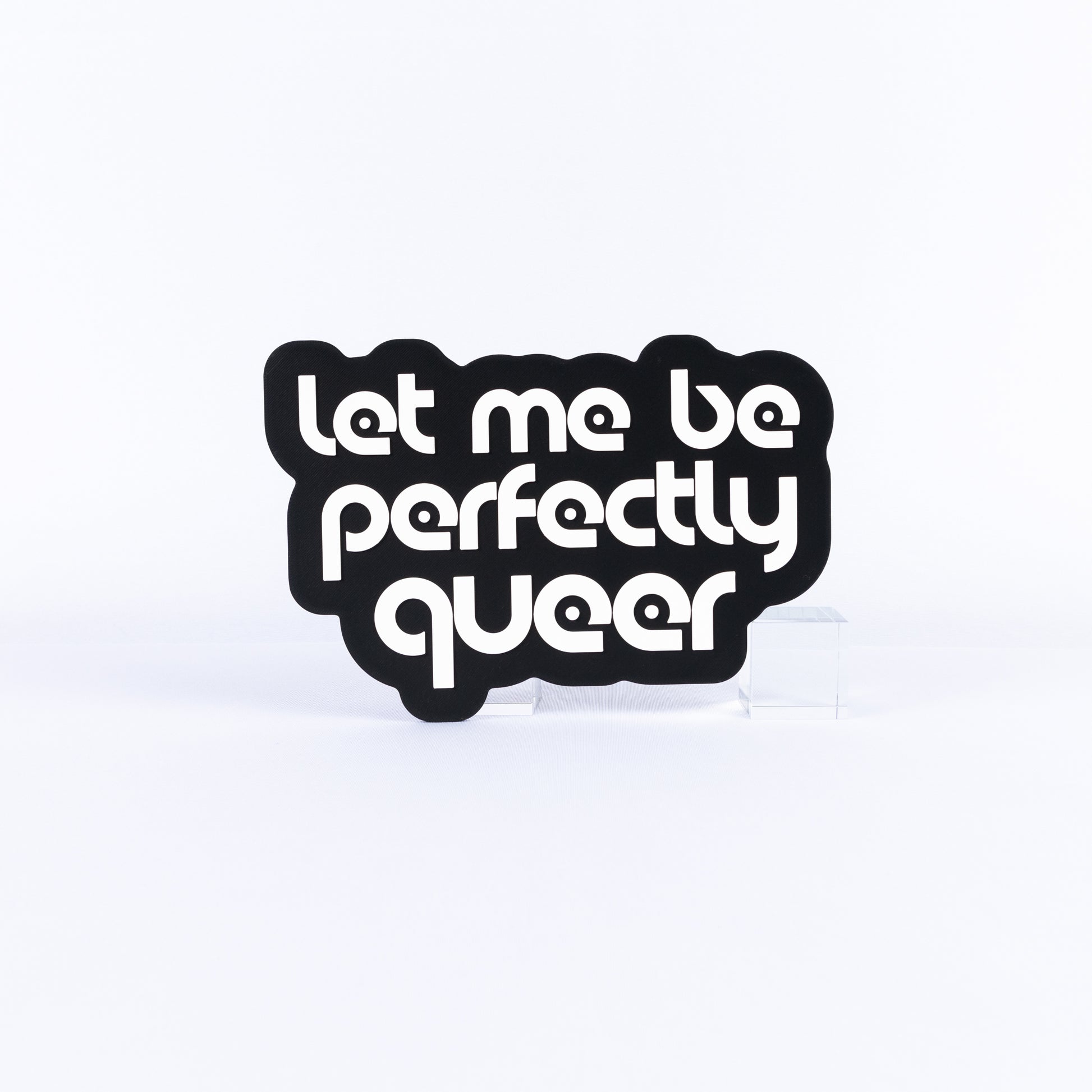 Black and white sign with white text 'Let me be perfectly queer' on a white background