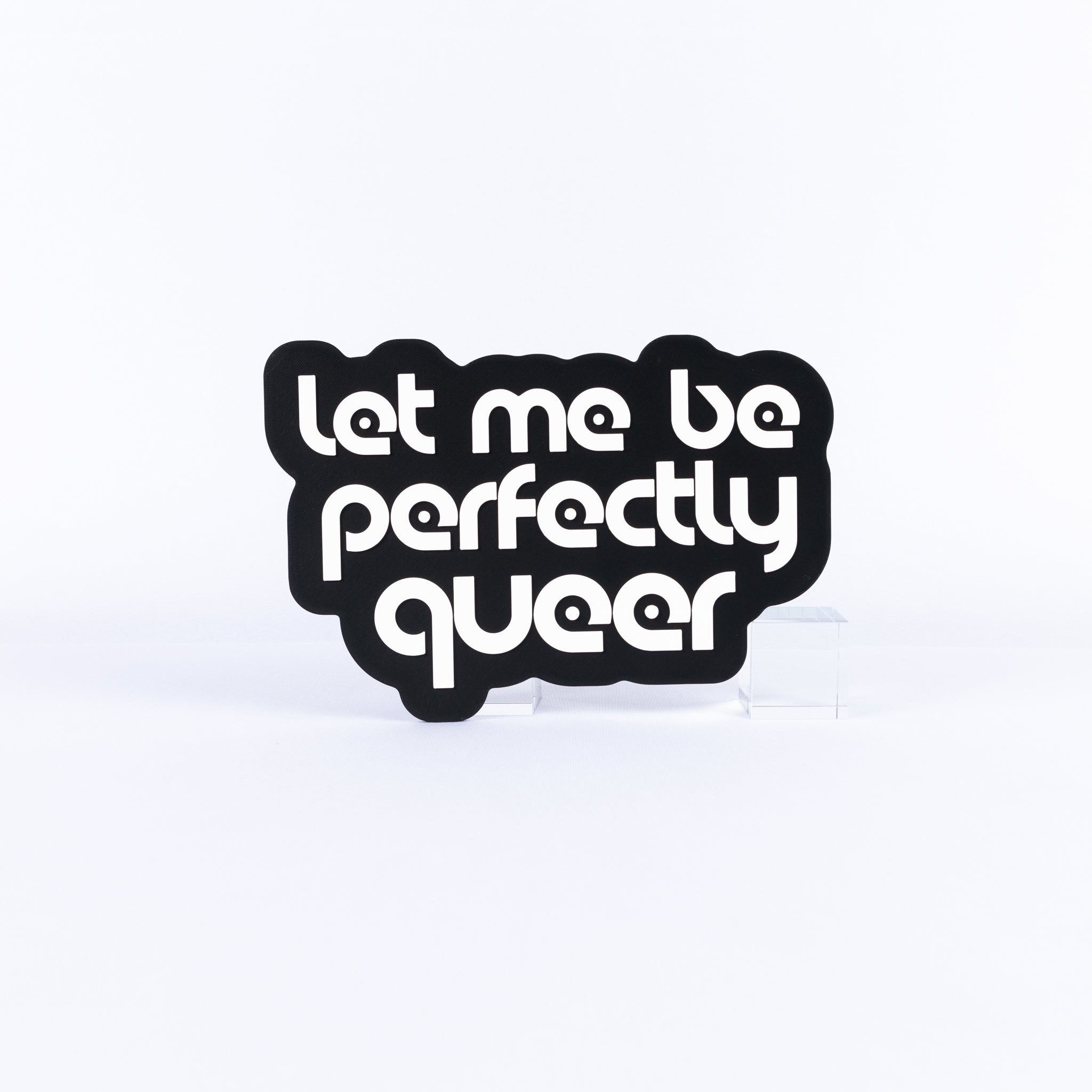 Black and white sign with white text 'Let me be perfectly queer' on a white background