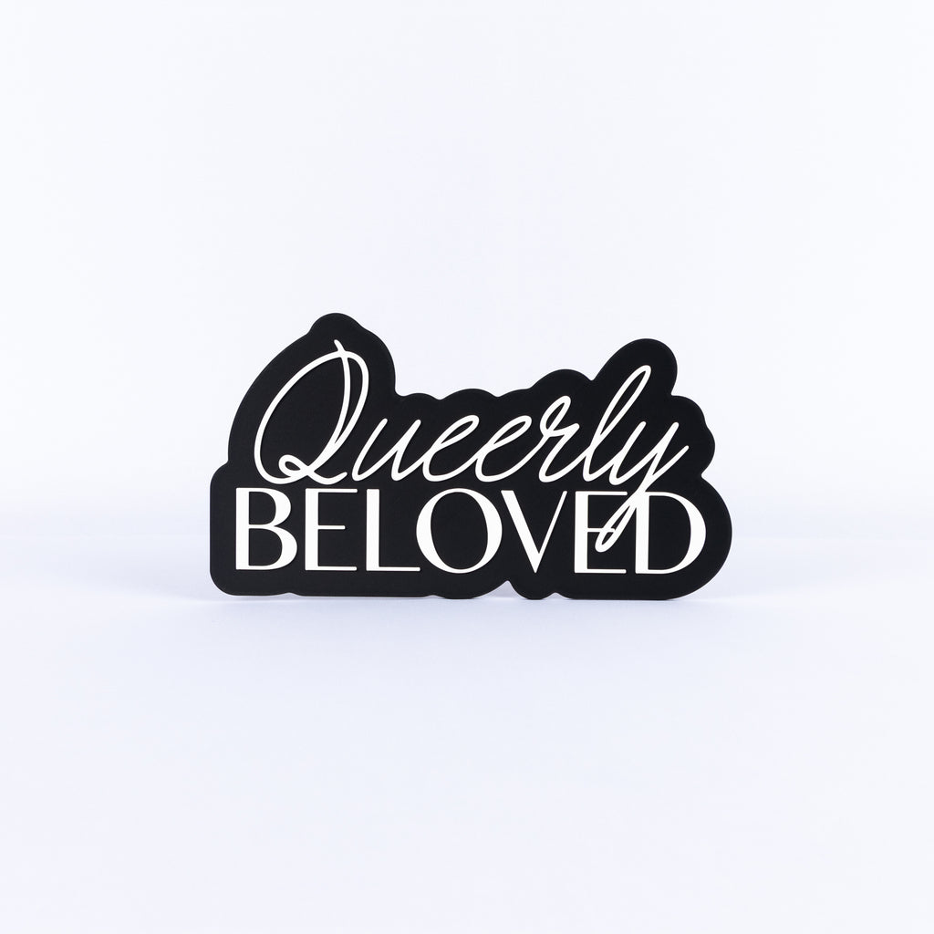 Black and white sign with 'Queerly Beloved' text on a white background