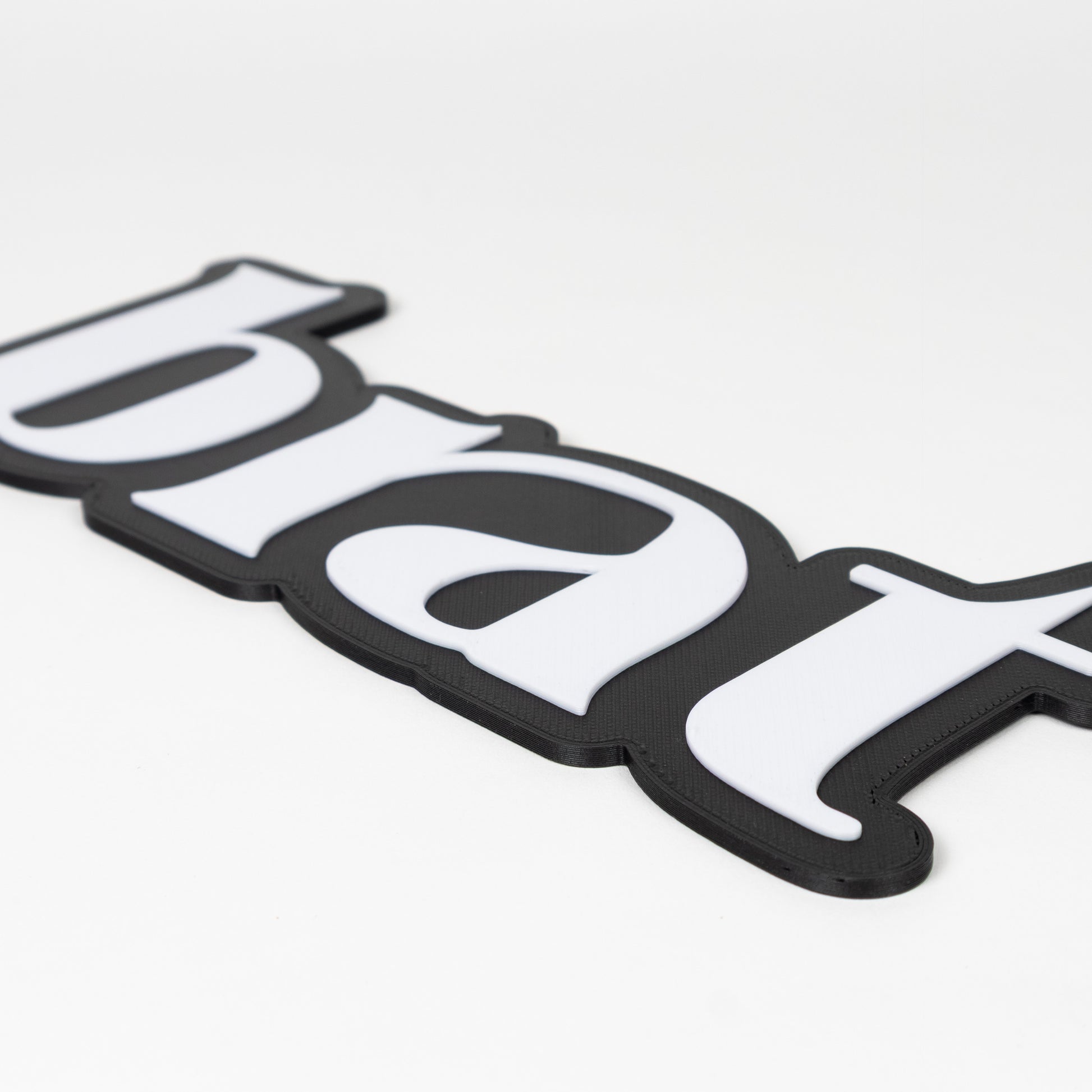Black and white brat sign photo booth prop, close up of raised white lettering