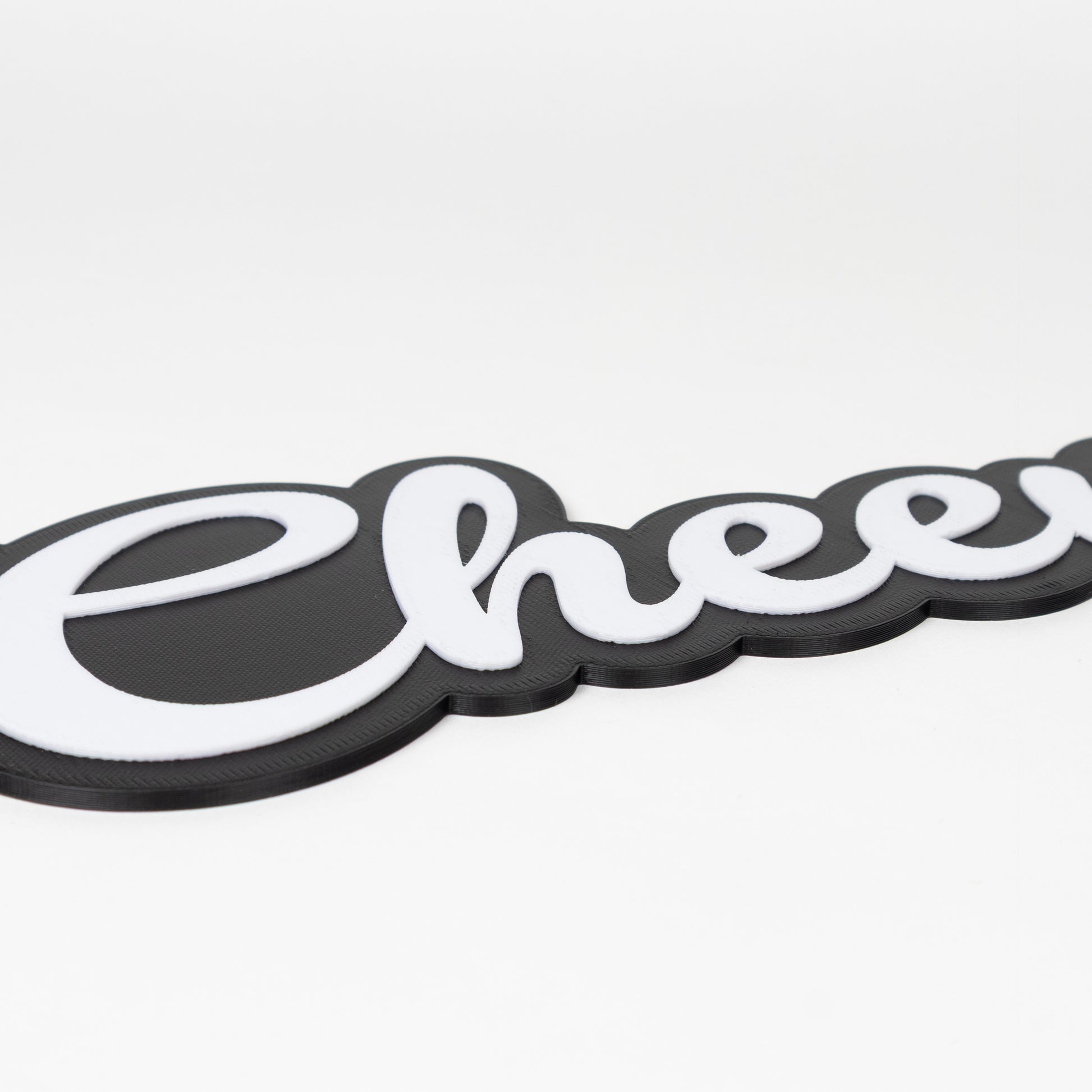 "Cheers!" photo booth prop sign with a matte black base and raised white lettering on a white background.