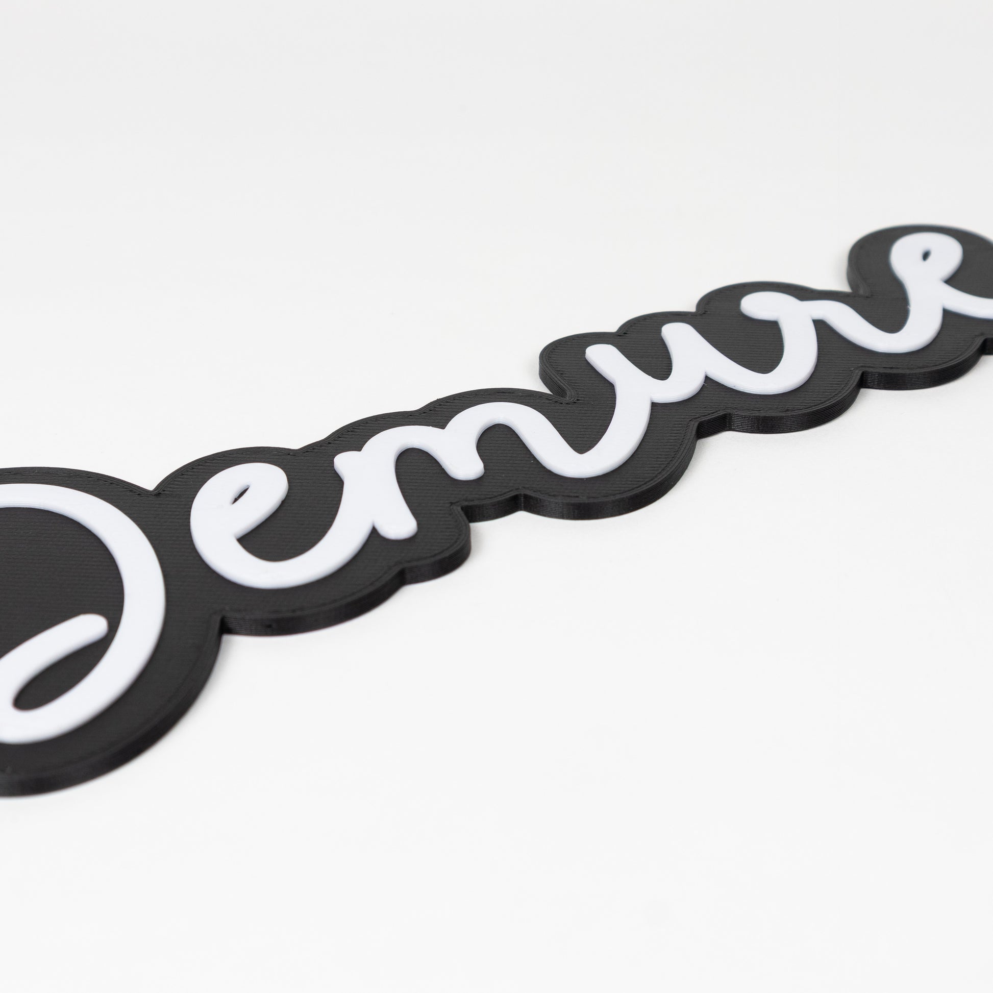 Black and white 'Demure' photo booth prop sign on a white background. Close up on raised white lettering.
