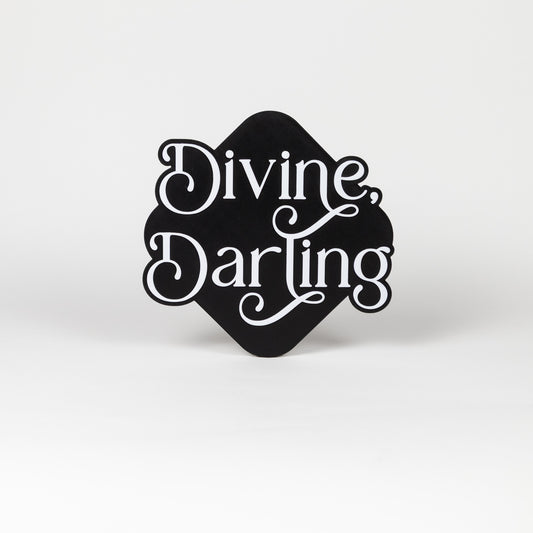 Black and white photo booth prop with 'Divine, Darling' text on a white background.