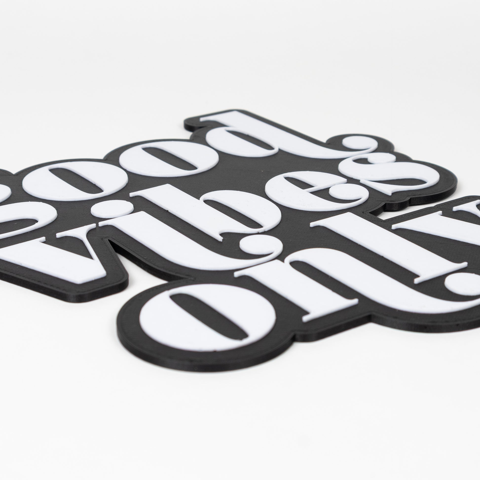 Close up shot of a black and white photo booth prop that reads "good vibes only". Features raised white text on a black base.