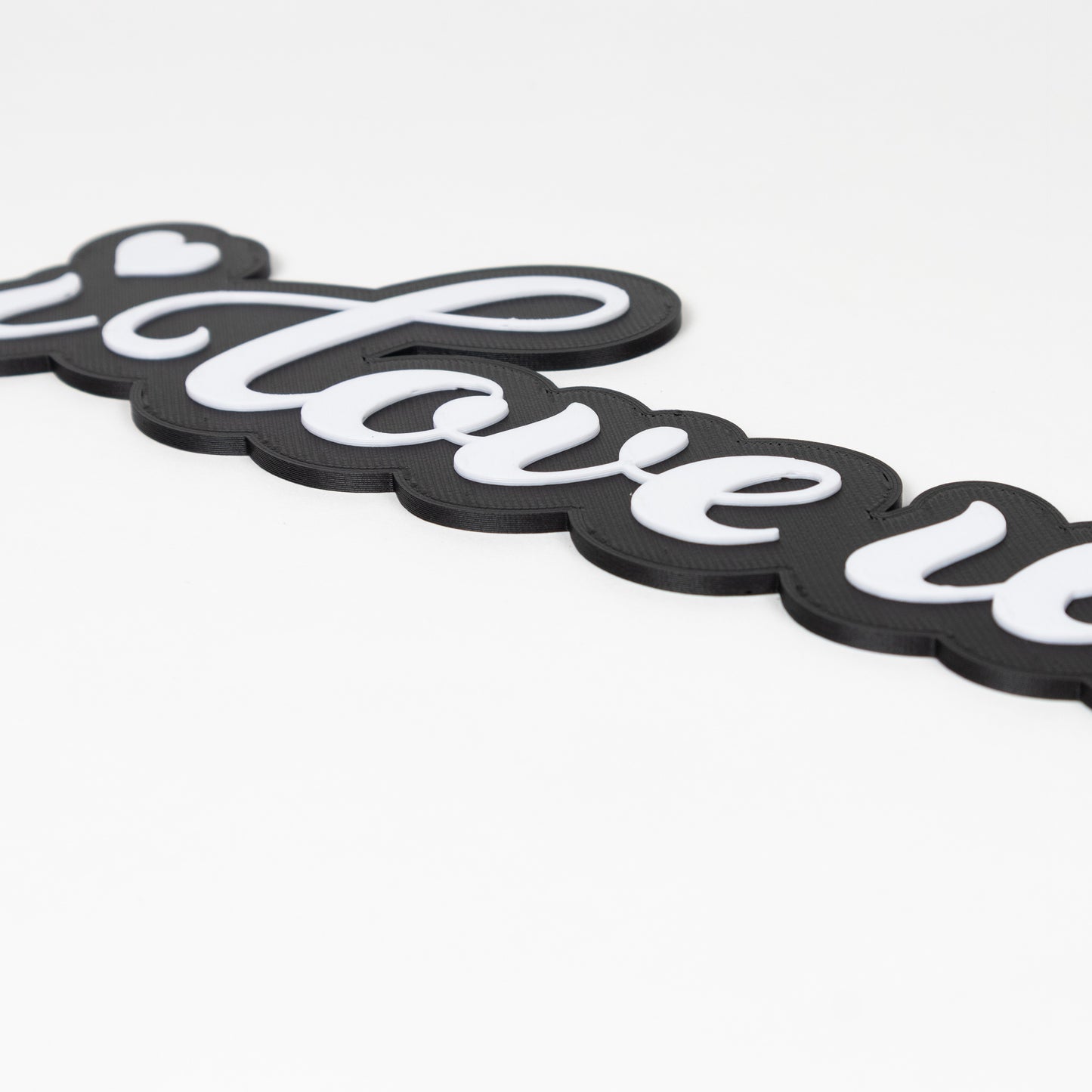 Close up shot of raised white text on a black base. Photo booth prop sign says "i love us"