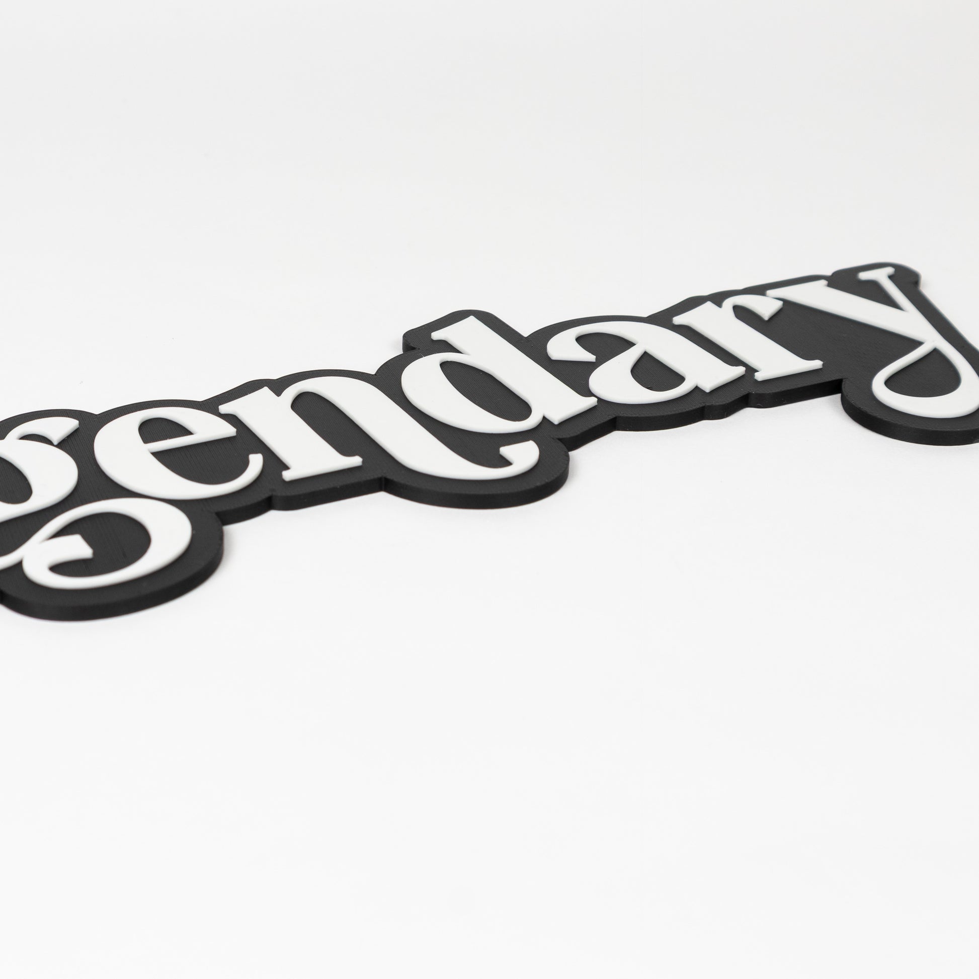 Close up shot of a photo booth prop sign. Black base with raised white 'legendary' text on a white background