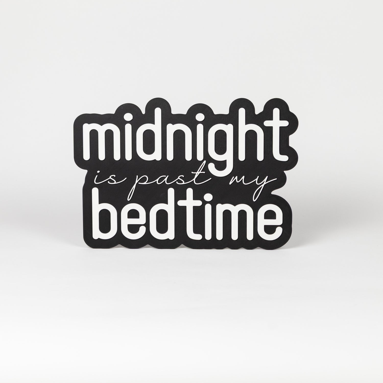 Photo booth prop sign. Black base with 'midnight is past my bedtime' white text on a white background