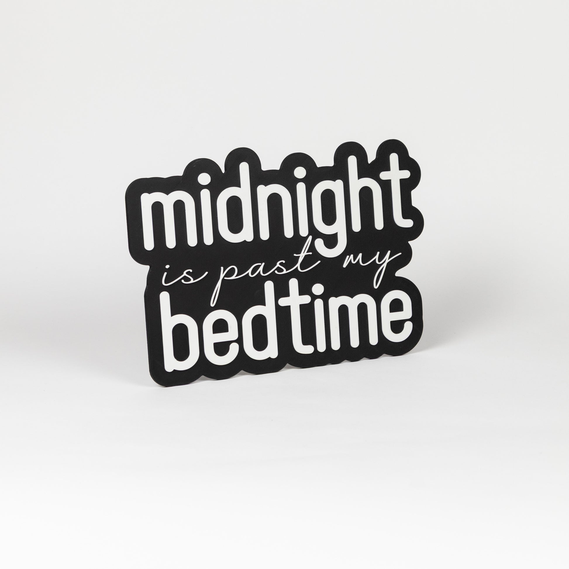 Photo booth prop sign. Black base with 'midnight is past my bedtime' white text on a white background
