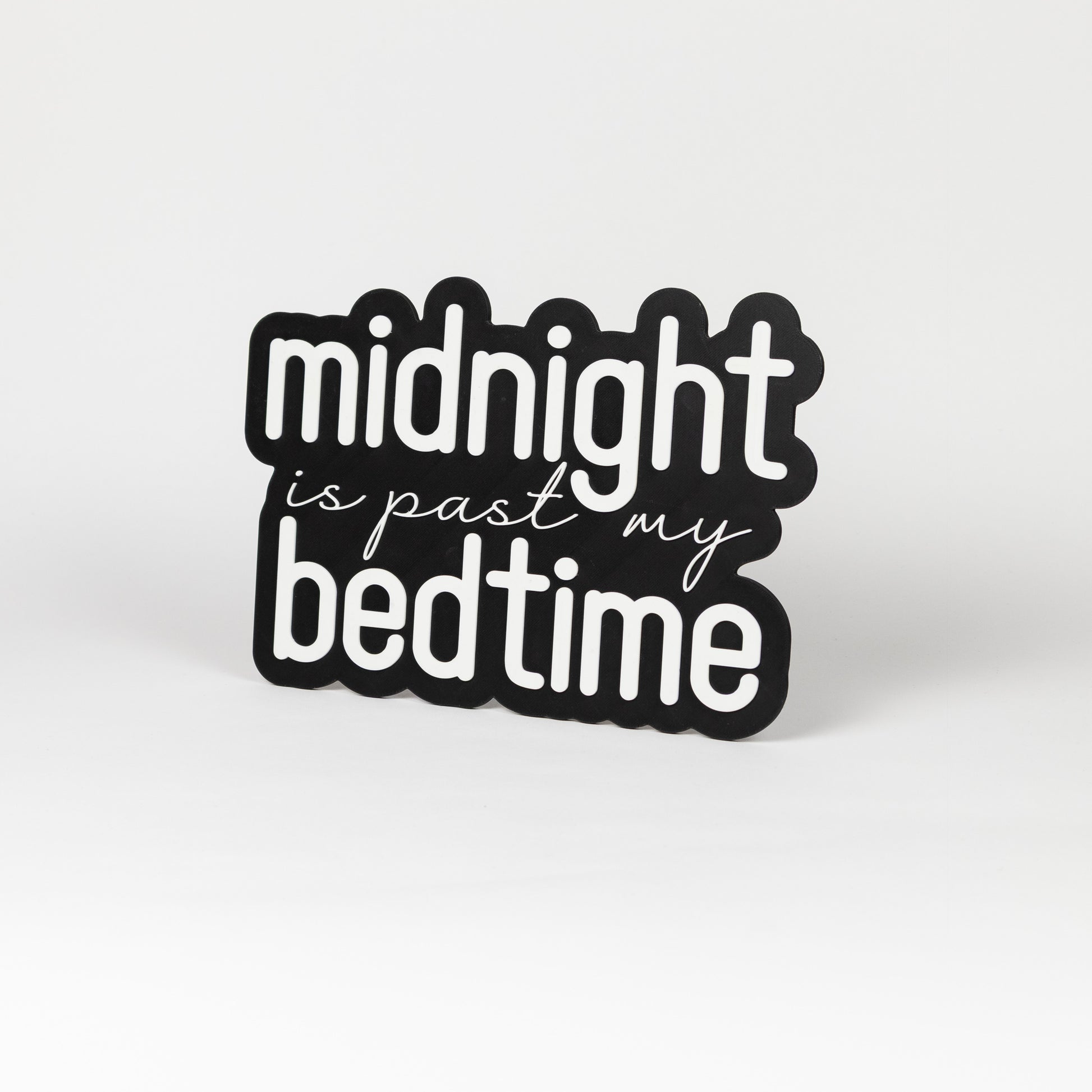 Photo booth prop sign. Black base with 'midnight is past my bedtime' white text on a white background