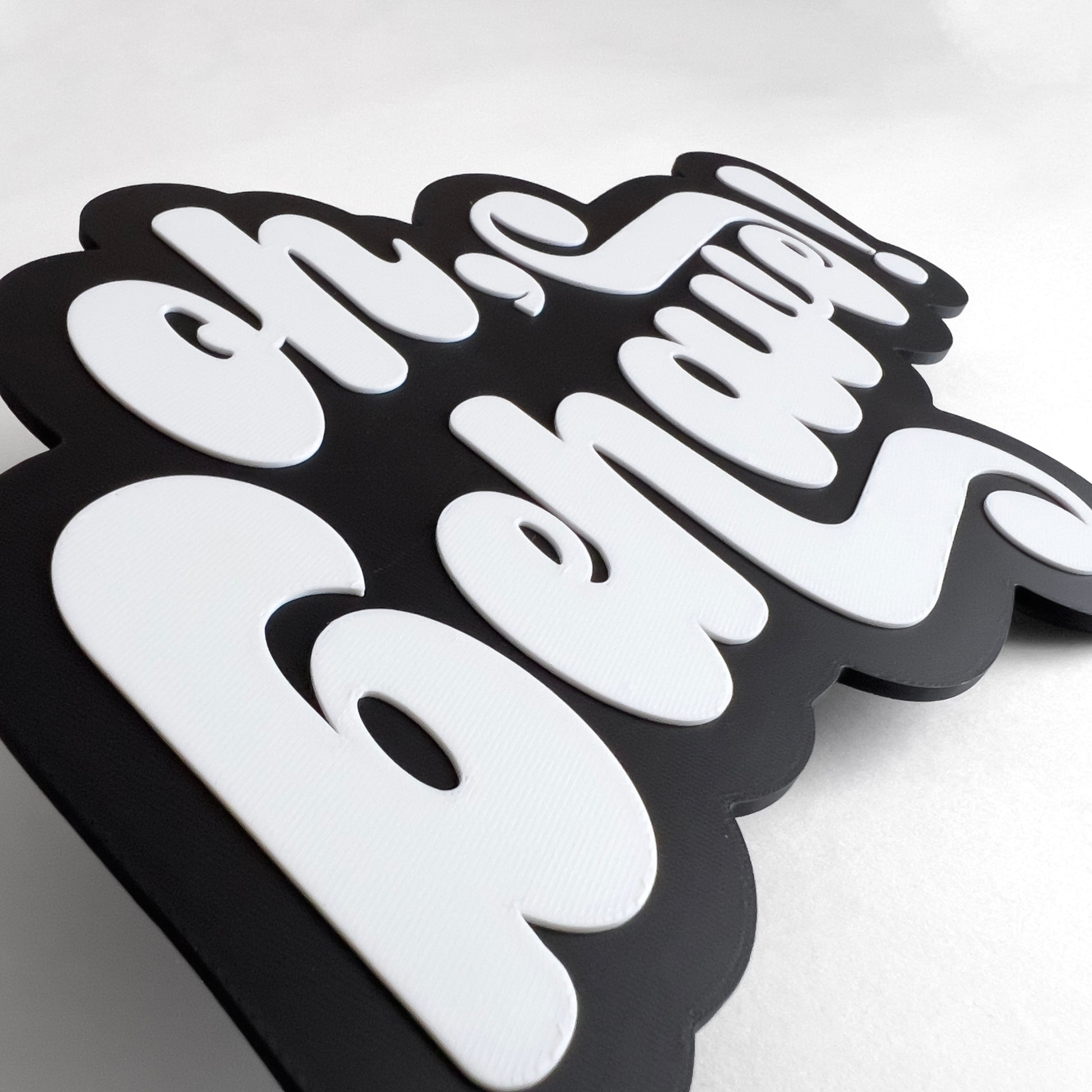 Close up of a black and white photo booth prop sign that says "oh, behave!". Shows raised lettering.