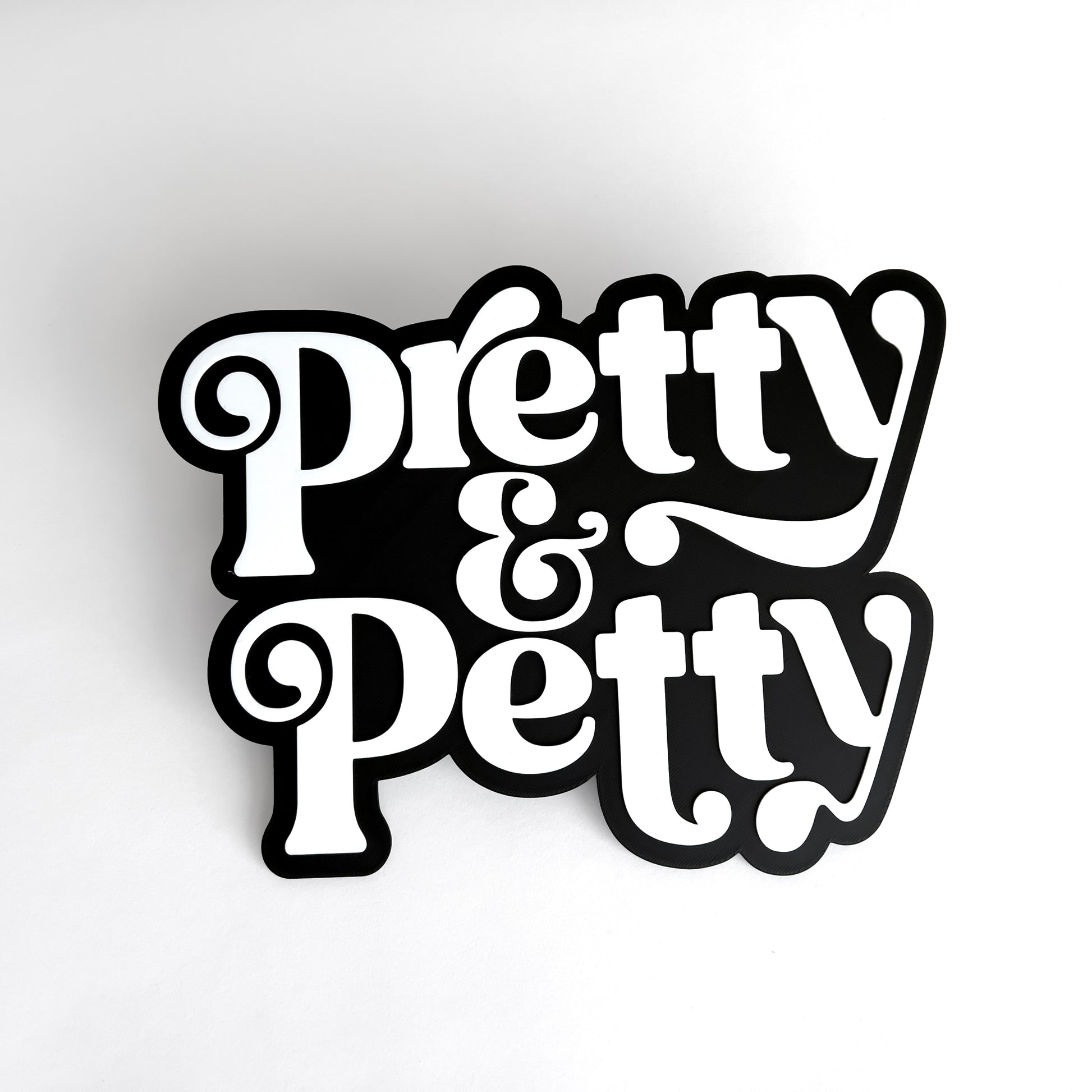 Black and white sign that says "Pretty and Petty" for photo booth events.