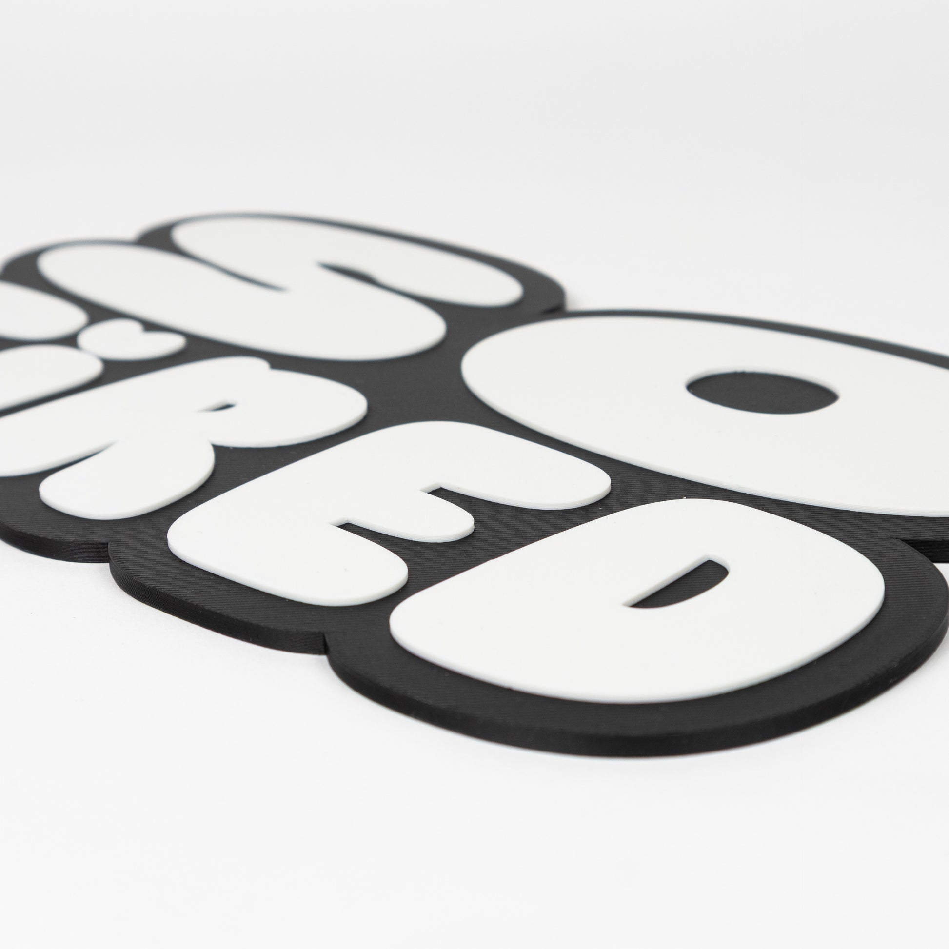 Close up of black and white "So Tired" sign that shows raised white text on black silhouette base. Photo booth prop.