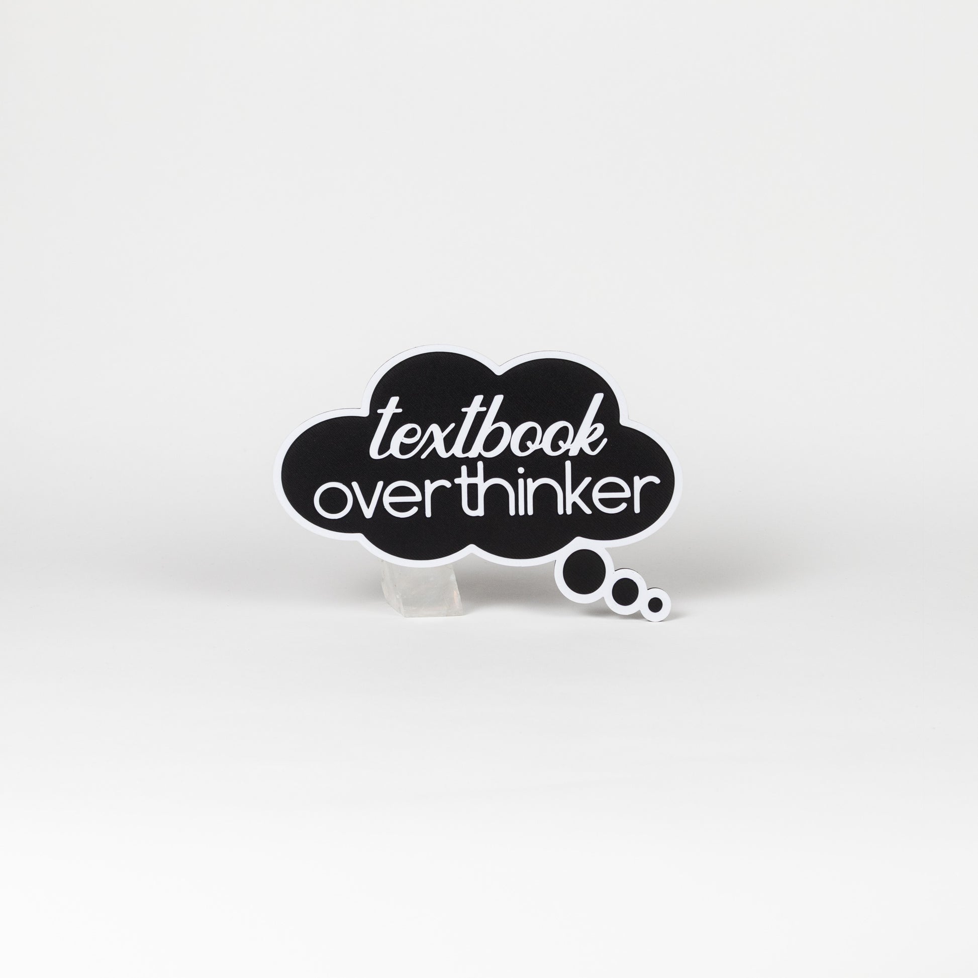 Black cloud-shaped sign with 'textbook overthinker' text in white. Photo booth prop shot on a white background.