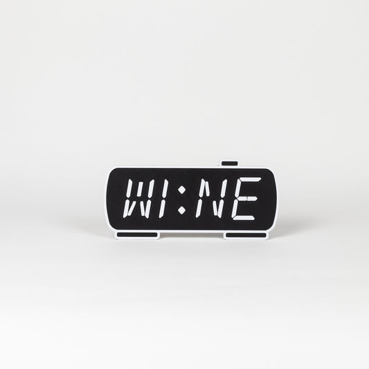 Black and white photo prop of a digital clock displaying 'WINE'. 